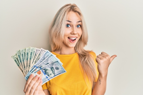 woman holding money while doing a thumbs up sign depicting affordability of heating oil