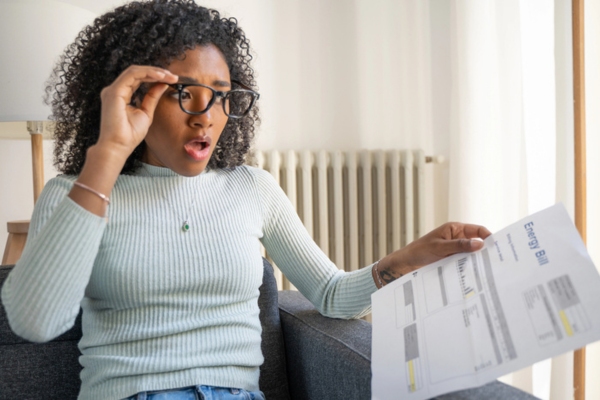 woman looking shocked while looking at energy bill