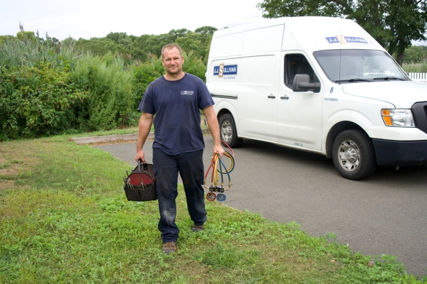 JJ Sullivan HVAC contractor carrying tools with service van behind