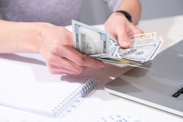 female hands counting dollar bills depicting increased winter expense