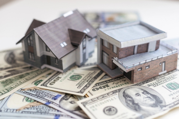 miniature house models on top of dollar bills depicting propane heating expenses