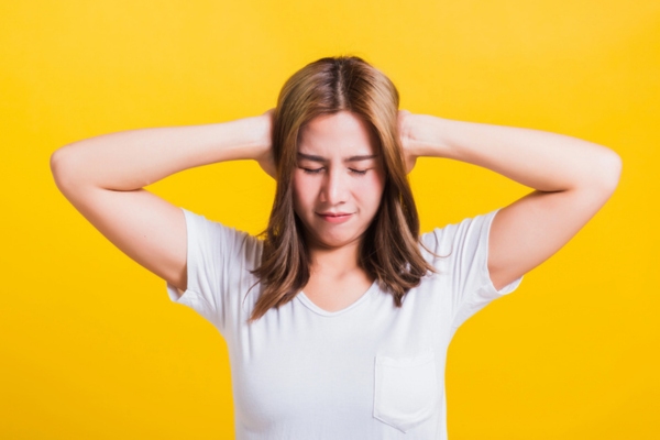 woman covering ears depicting overlooking AC warning signs